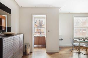 cocina con paredes blancas, mesa y ventana en The Sophisticated Apartment in Knightsbridge en Londres
