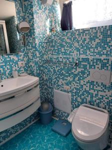 a bathroom with a toilet and a sink with blue tiles at Il Fienile in Tremosine Sul Garda +6 photos