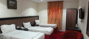 a hotel room with two beds and a chair at فندق اسكان وافر متوفر توصيل مجاني للحرم على مدار 24 ساعة in Makkah