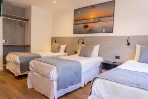um quarto de hotel com duas camas e um quadro na parede em TAS D VIAJE Suites - Hostel Boutique em Punta del Este