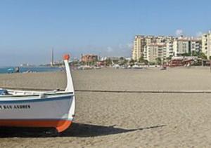 a boat sitting on the shore of a beach at Casa Martín Playa in Málaga