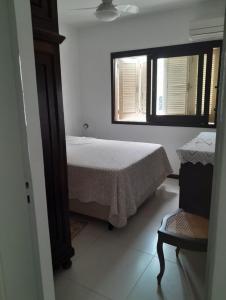a bedroom with a bed and a window and a chair at Apartamento ótima localização in Torres