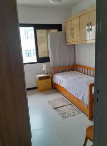 a small bedroom with a bed and a window at Apartamento ótima localização in Torres