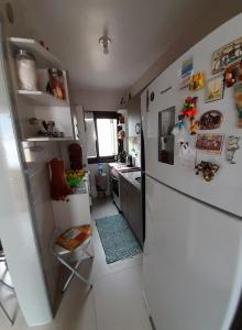 a kitchen with a refrigerator with many magnets on it at Apartamento ótima localização in Torres