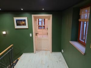 un pasillo verde con una puerta blanca y una escalera en Gästehaus Merlin, en Bad Bergzabern