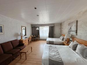 a hotel room with a bed and a couch at Hotel La Caravelle in Baie-Comeau +23 photos