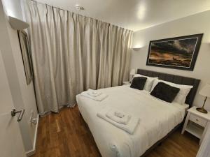 a bedroom with a white bed with two towels on it at Luxury Apartment in Canary Wharf in London