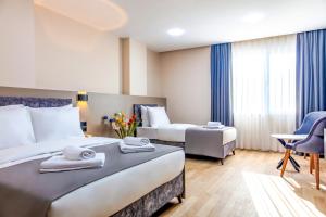 um quarto de hotel com duas camas e uma cadeira em The Business Class Hotel em Istambul