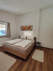 1 dormitorio con 1 cama con paredes blancas y suelo de madera en Apart Anna & Anton, en Brandberg