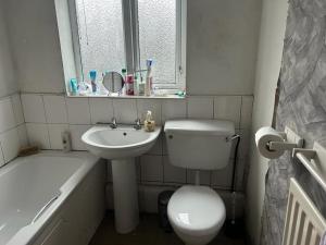 een badkamer met een toilet, een wastafel en een bad bij Heywood in Heywood