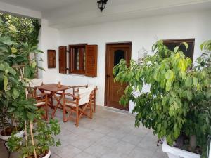 un patio con mesa de madera, sillas y plantas en Veroniki Studios, en Kokkari