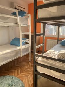 a room with three bunk beds and an orange wall at Blue Orange Hostel in Skopje