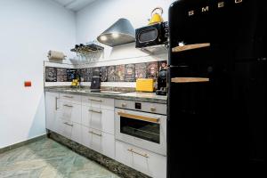 una cucina con armadietti bianchi e frigorifero nero di The Queen House a Málaga