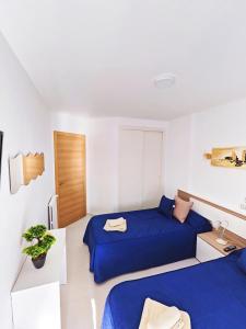 ベニドルムにあるPiso Lux Marのブルーシーツ付きの客室内のベッド2台
