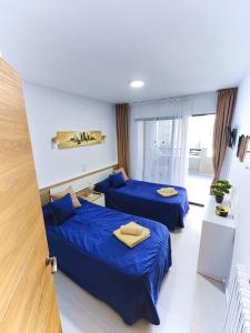 two beds in a hotel room with blue sheets at Piso Lux Mar in Benidorm