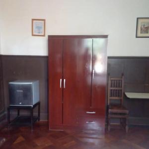 a wooden cabinet with a tv and a chair at Hostal María Luisa Bombal in Viña del Mar