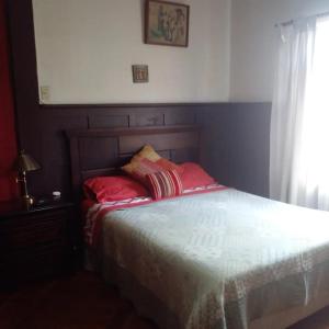 Un dormitorio con una cama con almohadas rojas y una ventana en Hostal María Luisa Bombal en Viña del Mar