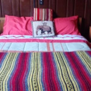 a bed with a colorful blanket and a picture on it at Hostal María Luisa Bombal in Viña del Mar
