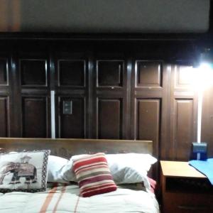 a bedroom with a wooden headboard and a bed with pillows at Hostal María Luisa Bombal in Viña del Mar