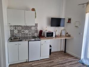 a kitchen with white cabinets and a counter with a microwave at Escapade Beaujolaise - Studio in Taponas +5 photos