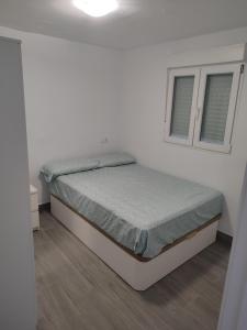 Bett in einem weißen Zimmer mit 2 Fenstern in der Unterkunft Playgarza relax in Telde