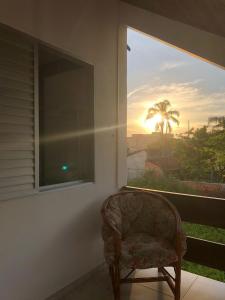 a chair sitting in front of a window with the sunset at Canto Santo in Itapoa
