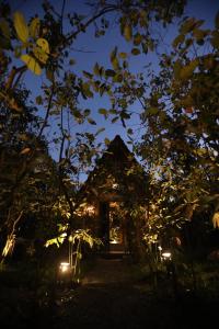 une maison est éclairée la nuit avec des lumières dans l'établissement Cinnamon Paradise Nature Room, à Ahangama