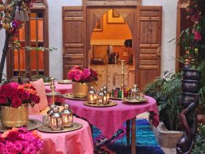 a room with two tables with candles and flowers at Riad Jnane d'&Ocirc; in Marrakech