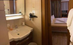 a bathroom with a sink and a mirror and a bed at Landhaus Engadin in Nauders