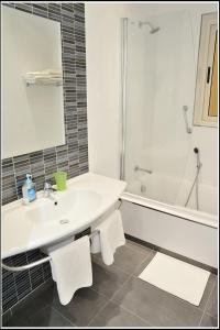 La salle de bains est pourvue d'un lavabo, d'une baignoire et d'une douche. dans l'établissement Villa Lyss Apartment 1, à Mellieħa