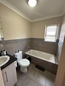 a bathroom with a toilet and a tub and a sink at Home away from Home in Pretoria