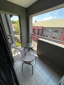 a balcony with two tables and chairs and two windows at Home away from Home in Pretoria