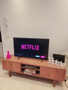 una TV a schermo piatto seduta sopra un centro di intrattenimento in legno di Bovio 33 Napoli art apartment a Napoli