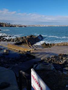 a rocky beach with the ocean and a sign at Созополис MORE SUN- Созопол in Sozopol