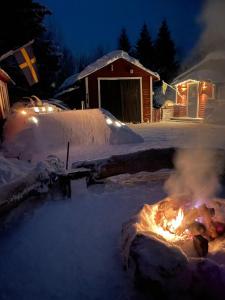una hoguera en la nieve frente a una casa en Schnieder's Stuga, en Harmånger