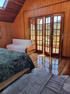 two beds in a room with wooden walls and wooden floors at Pousada nevadas da Serra in Urupema