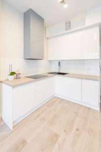 a kitchen with white cabinets and a wooden floor at Hanza Tower De Lux apartament in Szczecin