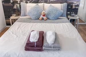 a white bed with towels and a teddy bear on it at Pyjamagetaways in London