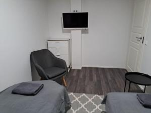 a room with a bed and a chair and a television at Rahkeen majoitus in Joensuu