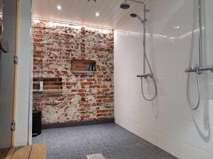 a bathroom with a brick wall and a shower at Rahkeen majoitus in Joensuu