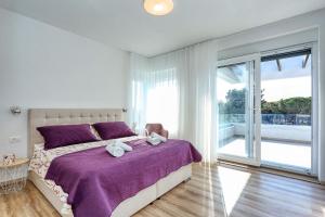 a bedroom with a bed with purple sheets and a window at Villa Linda in Zaton