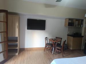 a room with a table and chairs and a television on the wall at Flat Miguel Pereira in Miguel Pereira