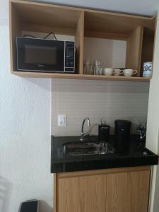 a kitchen with a sink and a microwave at Flat Miguel Pereira in Miguel Pereira