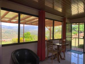 Zimmer mit einem Tisch, Stühlen und großen Fenstern in der Unterkunft Disfruta del contacto con la naturaleza in Puntarenas