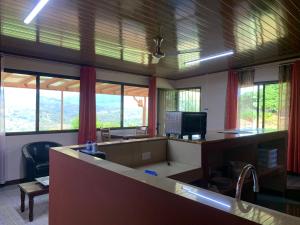 ein Büro mit einem Schreibtisch, einem Computer und Fenstern in der Unterkunft Disfruta del contacto con la naturaleza in Puntarenas