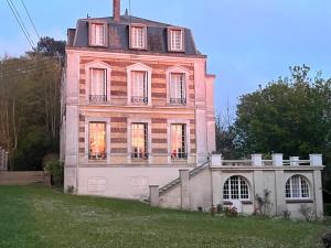 una vecchia casa su una collina erbosa con una scala di Royal Rose Etretat a Étretat