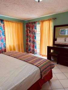 a bedroom with a bed and a desk and windows at Simply Mystical in Ocho Rios
