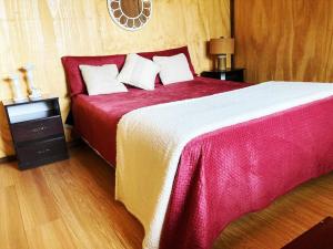 a bedroom with a large bed with red and white sheets at Cabaña 2 dormitorios cerca de Mágica Playa! in La Esmeralda 