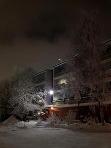um edifício à noite com árvores cobertas de neve em frente a ele em Vartiomaja - beautiful apartment near Arktikum em Rovaniemi