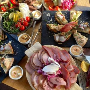 a table topped with plates of food with meats and vegetables at Pensiune & Restaurant Victoria in Păltiniş